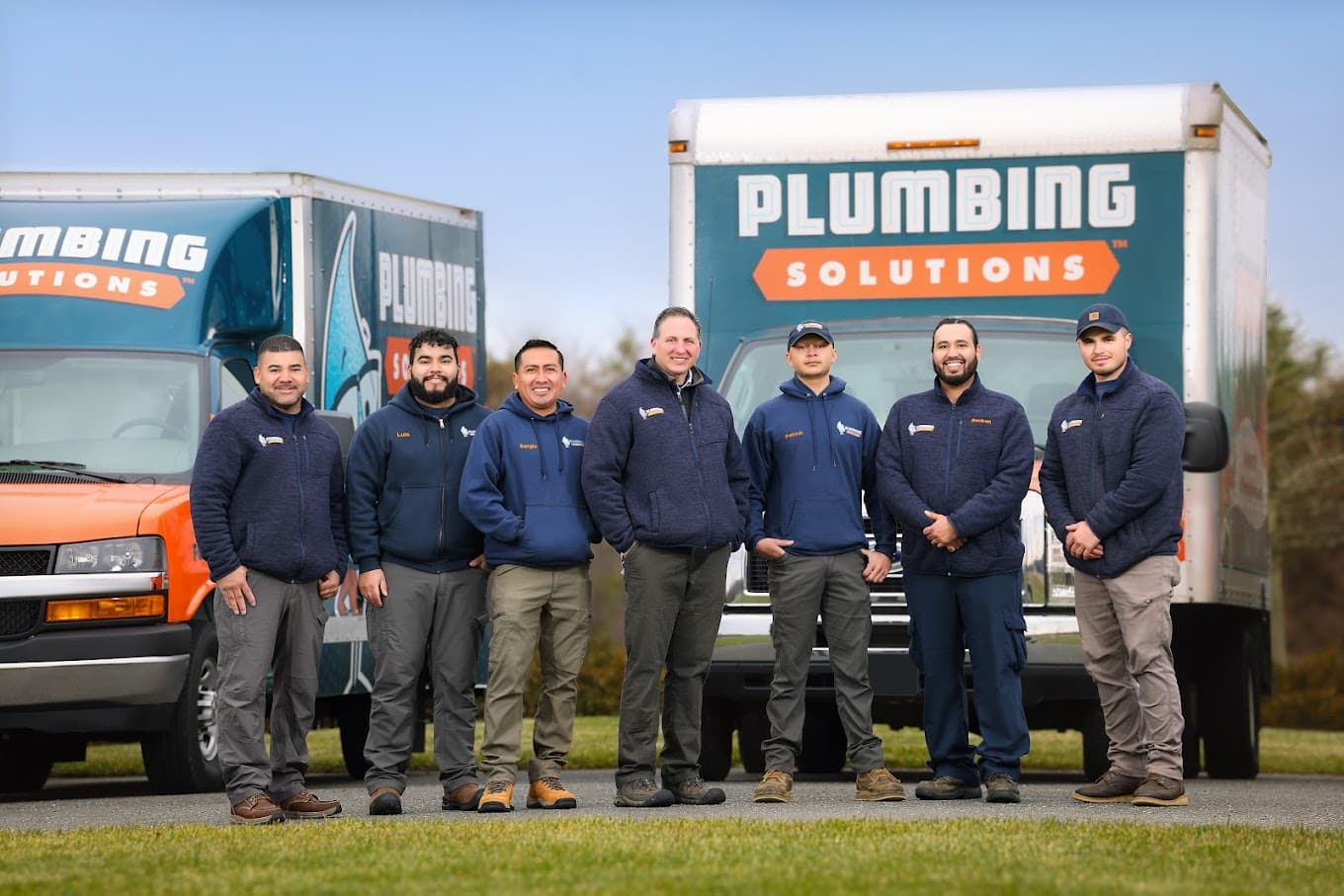 Plumbing Solutions Inc., team - standing in front of company trucks